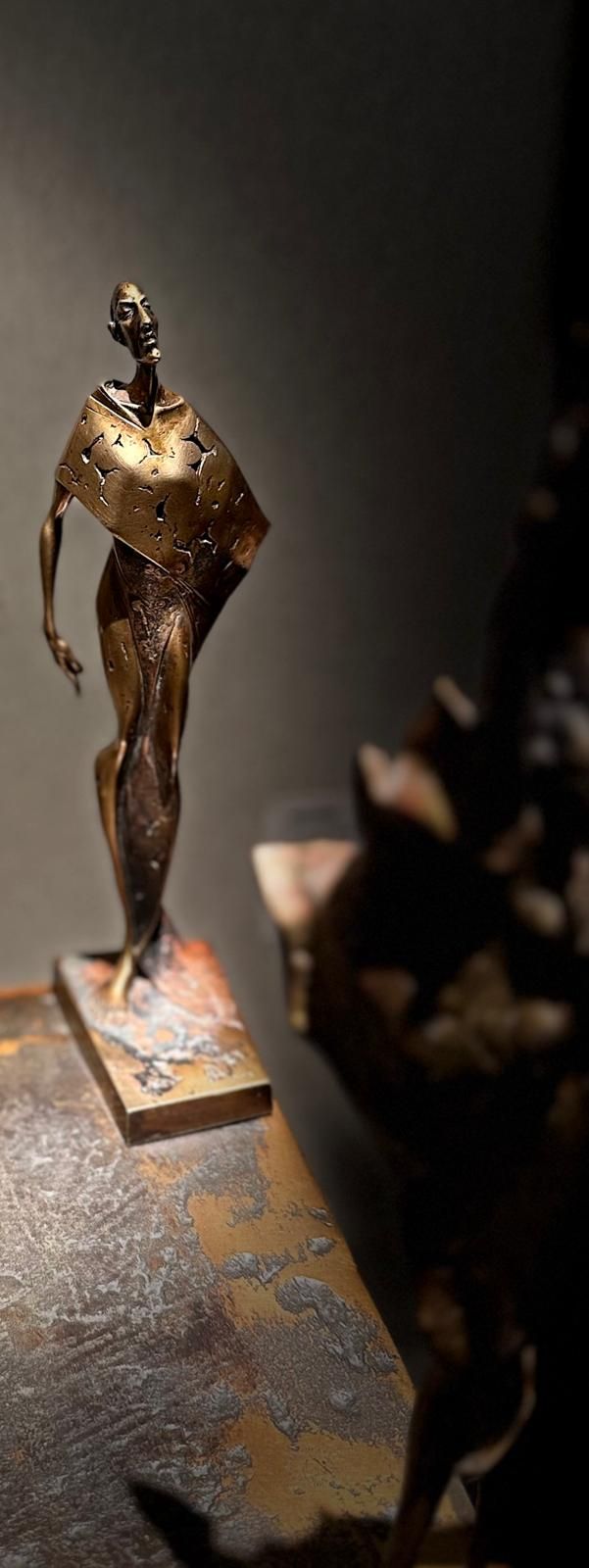 Skulptur „Herbst" aus CuSi3 Siliziumbronze (ca. 25 cm) auf Metallplatte; schlanke, abstrahierte Figur im Vordergrund mit nach oben gerichtetem Blick, dahinter zwei weitere Figuren unscharf vor grauer Galeriewand.
